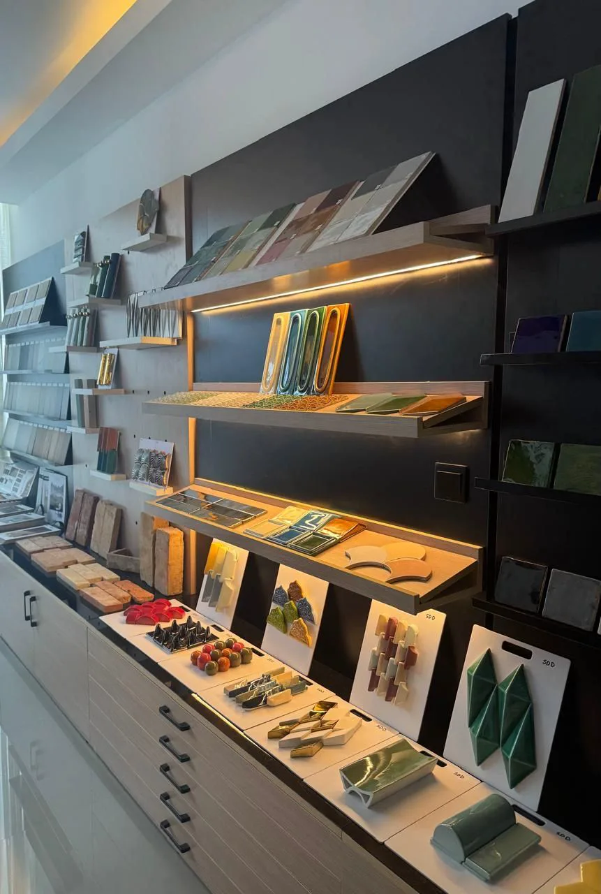 Handmade ceramic samples arranged across illuminated shelves in the MFZ studio.