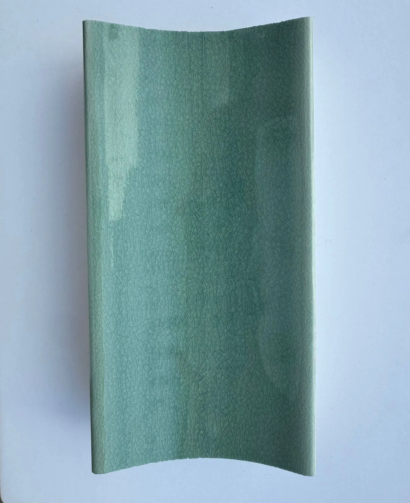 Curved sea-foam green glazed ceramic tile.