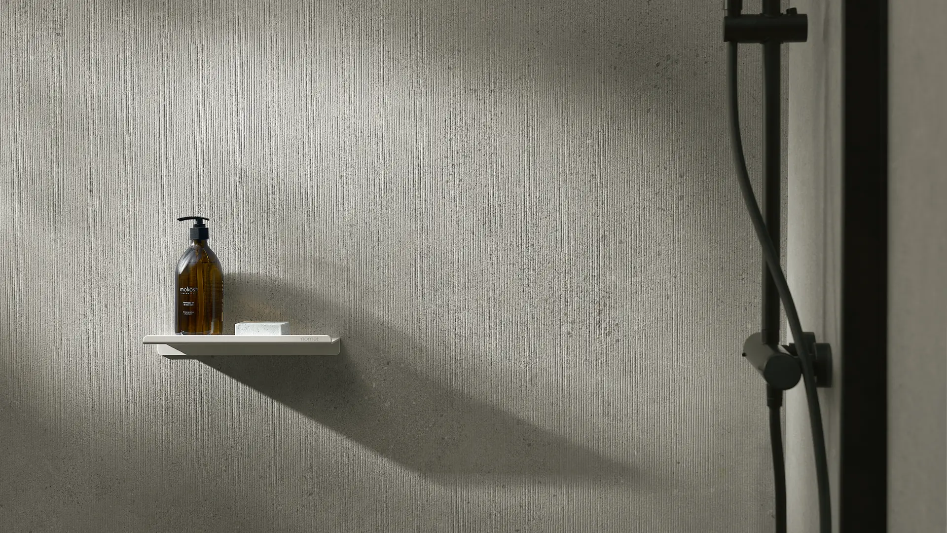 Minimalist bathroom with a textured grey MODEE mineral wall and a small floating shelf.