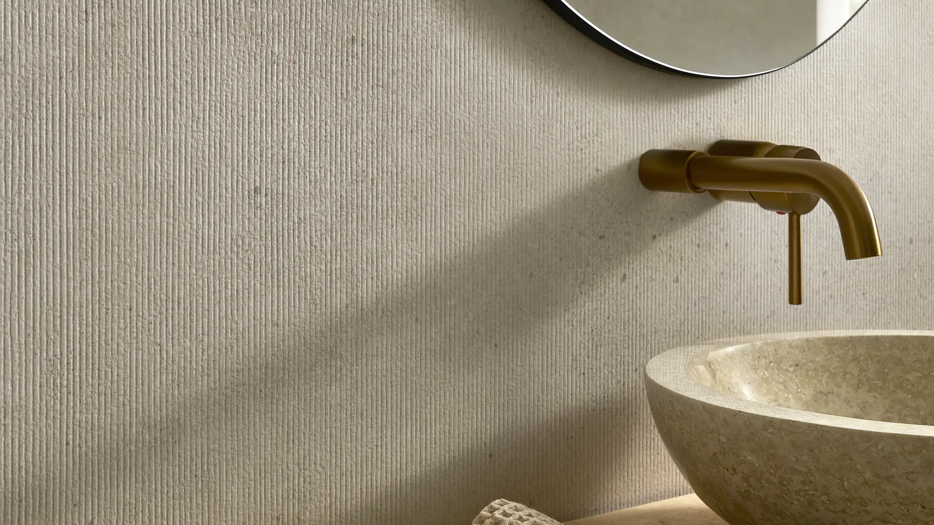 Modern bathroom with vertically striped wall panels, a brass faucet, and a stone basin.