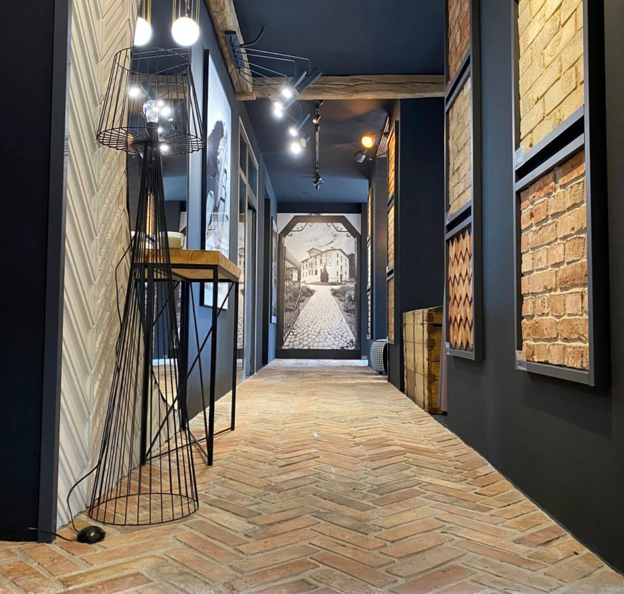Showroom hallway with reclaimed brick flooring and framed material displays.